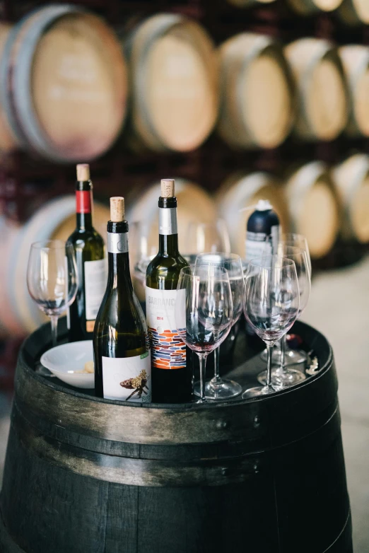 wine bottles and glasses are sitting on a barrel