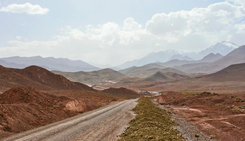 a dirt road with a bunch of mountains in the background