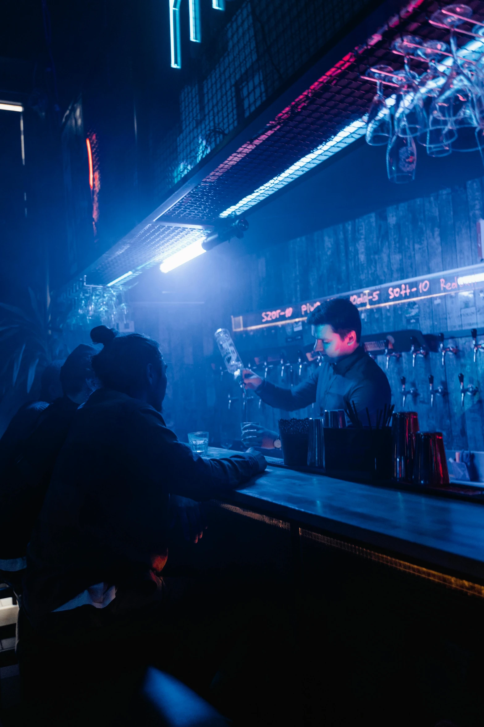 a group of people sitting at a bar, dystopian lighting, cold beer, scene from a rave, slightly minimal