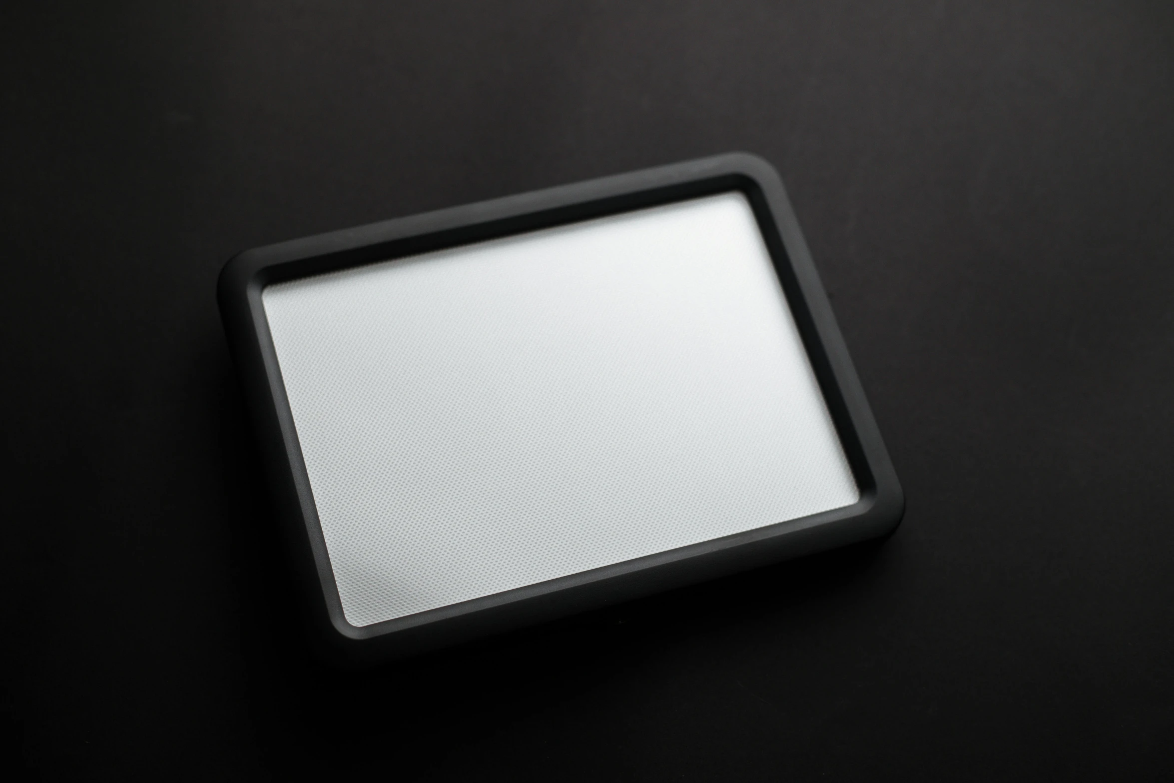 a tablet computer sitting on top of a black table, with a mirror, silicone cover, black border, product shot