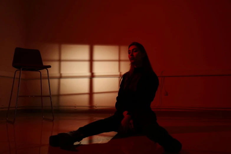 a woman sitting on the floor in a dark room, an album cover, inspired by Elsa Bleda, unsplash, realism, volumetric lighting. red, light and shadow effects, charli xcx, 5 feet away