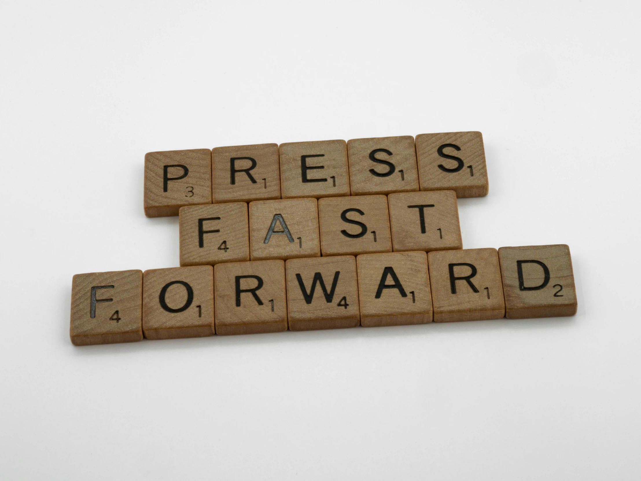 a set of scrabble tile letters spelling press fast forward