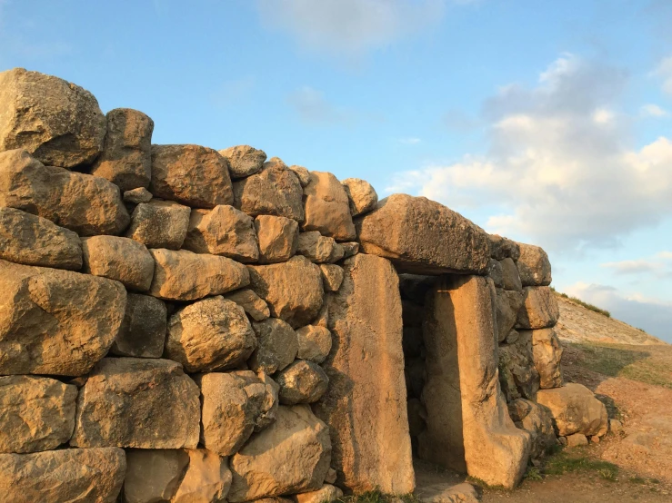 a stone structure sitting on top of a hill, an album cover, pexels contest winner, mingei, traditional corsican, giant tomb structures, 3 doors, morning lighting