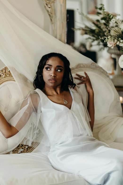 a woman in a white dress sitting on a couch, inspired by Edwin Austin Abbey, trending on pexels, baroque, soft silk dress, black young woman, wearing a wedding dress, high angle