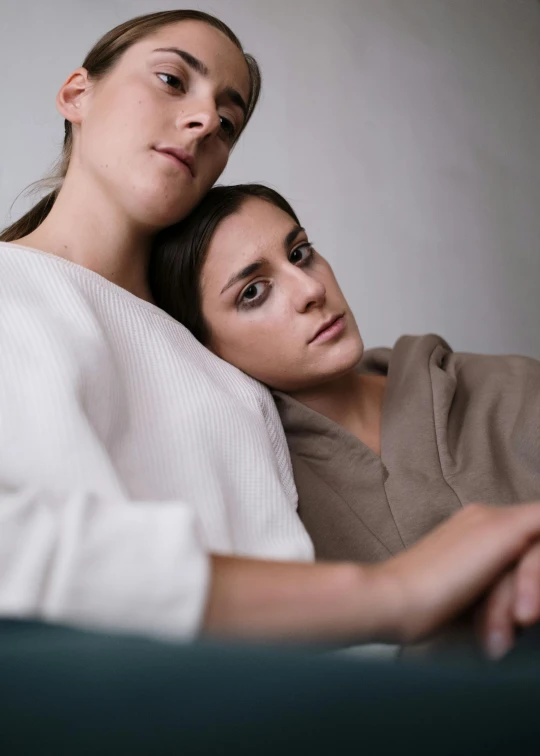 two women sitting next to each other on a couch, inspired by Nan Goldin, trending on unsplash, serial art, intricate heterochromia sad, lesbian embrace, soft portrait shot 8 k, androgynous male