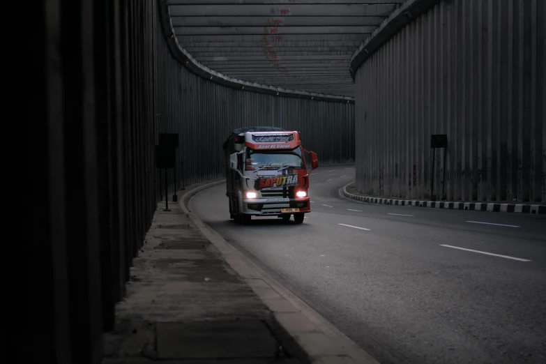 a red fire truck driving through a tunnel, a picture, by Adam Marczyński, pexels contest winner, hyperrealism, jakarta, grey, rectangle, late morning