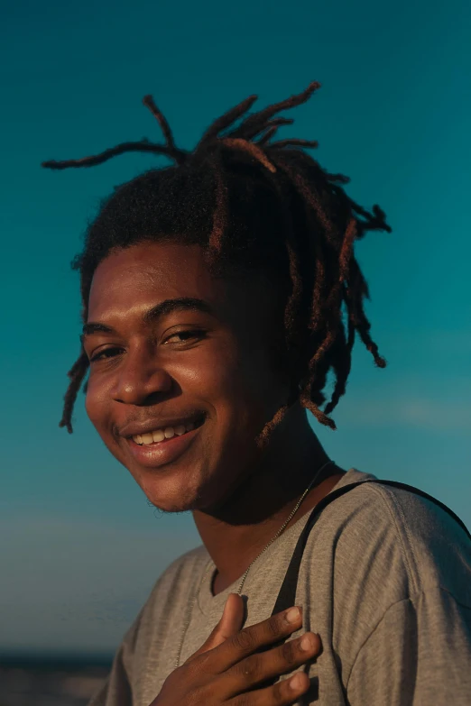 a man with dreadlocks smiles at the camera, trending on unsplash, he looks like tye sheridan, black teenage boy, low quality footage, (golden hour)