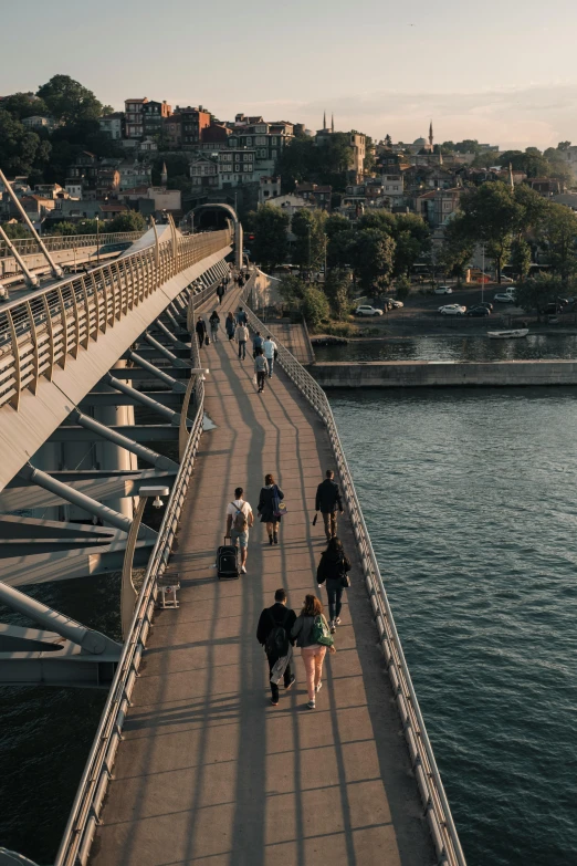 a group of people walking across a bridge, photo of zurich, nice afternoon lighting, zoomed out to show entire image, seaside