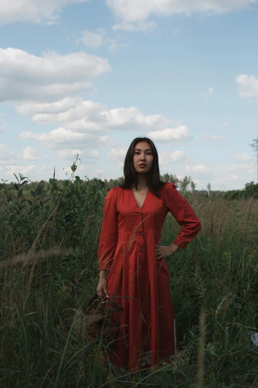 a woman in a red dress standing in tall grass