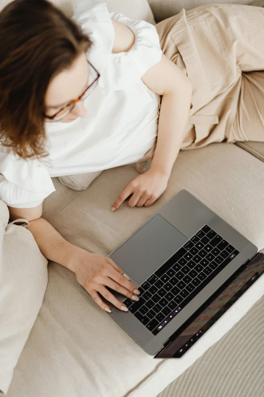 a woman laying on a couch using a laptop, trending on pexels, high angle close up shot, rounded lines, developers, thumbnail