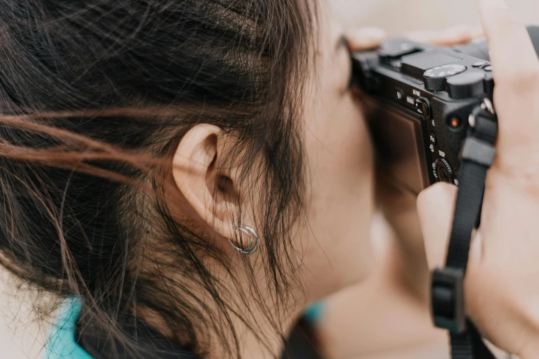 a woman taking a picture with a camera, by Adam Marczyński, trending on pexels, photorealism, close up shot from the side, an asian woman, side of head, shot from the back