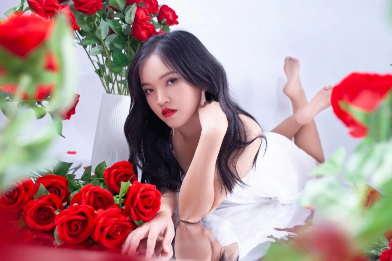 the woman is posing for the camera in her white dress with red roses