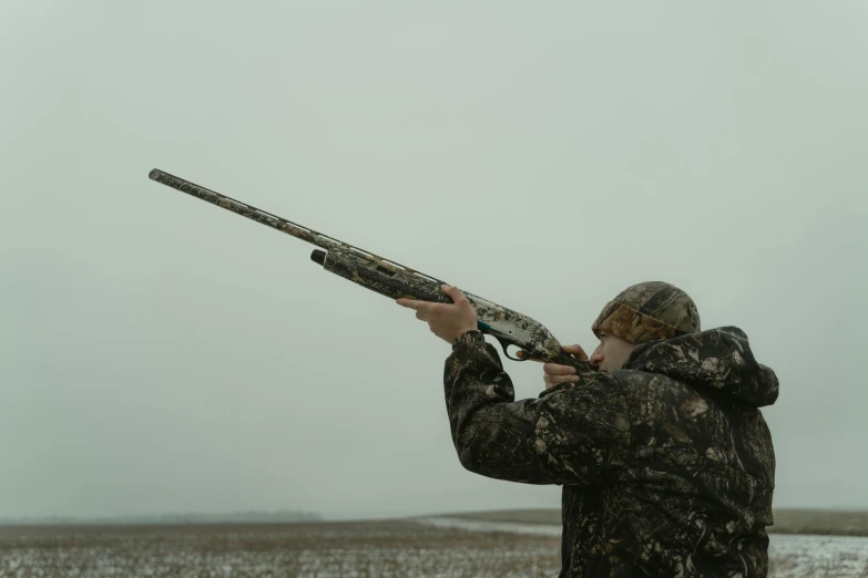 a man standing in a field holding a rifle, tundra, double barrel shotgun, shot with sony alpha, camo
