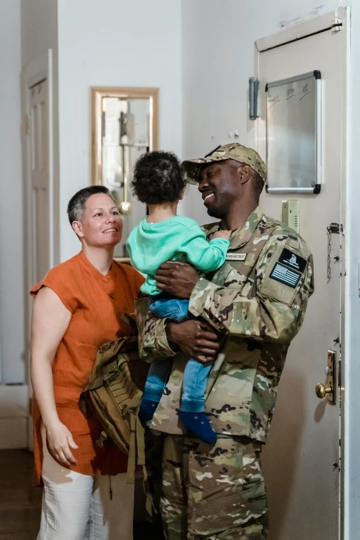 a man in a military uniform holding a child, about to enter doorframe, amanda clarke, jemal shabazz, profile image