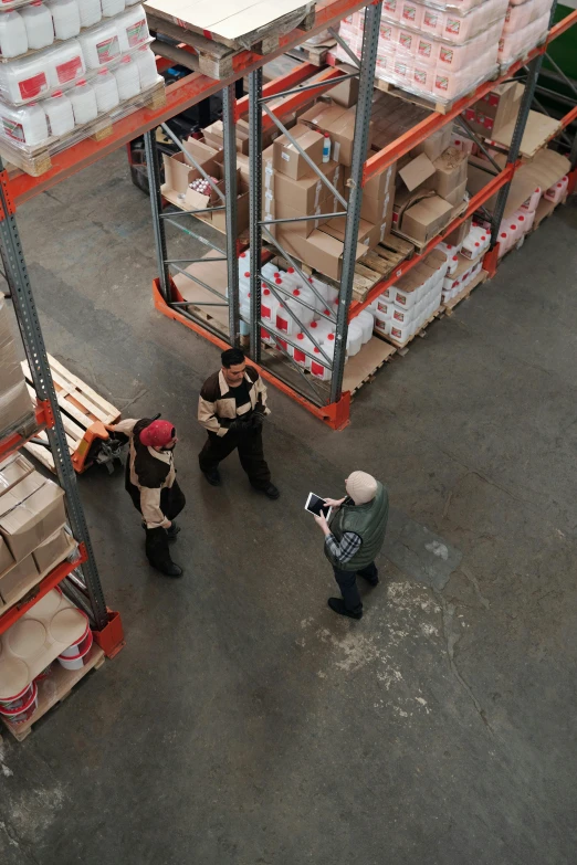 a group of men standing next to each other in a warehouse, pexels contest winner, aerial shot, inspect in inventory image, cardboard, brown