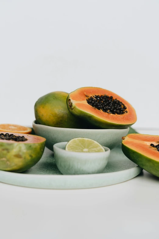 a white plate topped with sliced papanas, a still life, by Ryan Pancoast, unsplash, tropical fruit, celadon glaze, 6 pack, seeds