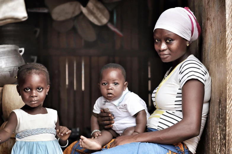 a woman sitting next to two small children, by Daniel Lieske, pexels contest winner, hurufiyya, adut akech, rustic, commercially ready, 15081959 21121991 01012000 4k