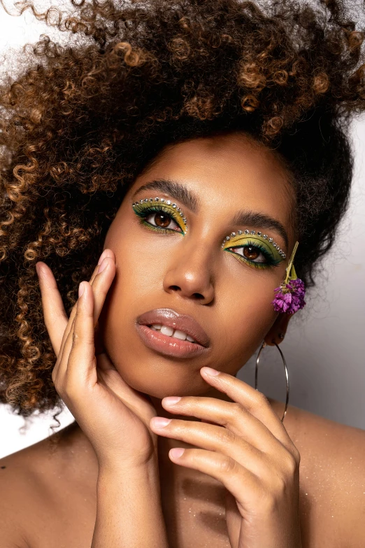 a woman with curly hair posing for a picture, inspired by Cosmo Alexander, trending on pexels, green magenta and gold, natural make-up, natural skin tones, hand on cheek