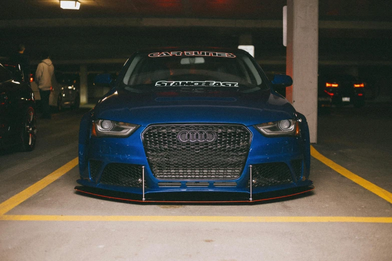 a blue audi car with red lettering parked in a parking garage