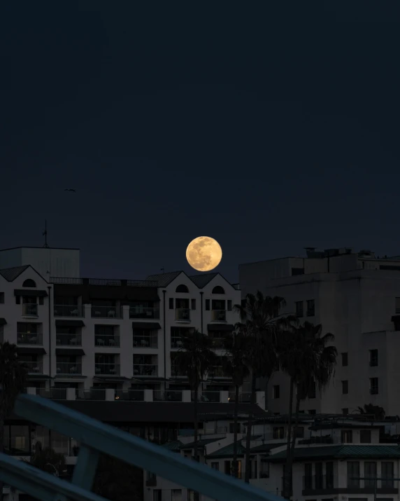 a full moon rises over a city at night, pexels contest winner, santa monica beach, mid-shot of a hunky, ☁🌪🌙👩🏾, hotel room