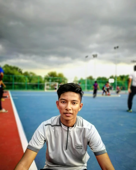 a man sitting on top of a tennis court holding a racquet, a picture, by Bernardino Mei, trending on dribble, low quality photo, childhood friend, on a football field, ((portrait))