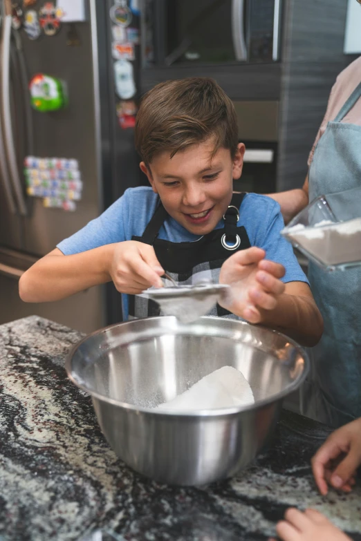 a boy with an apron is mixing a bowl of flour