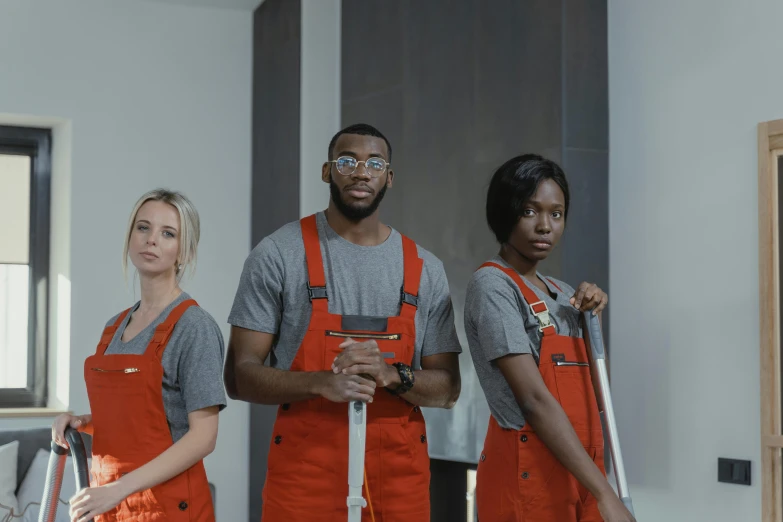 a group of people standing next to each other, inspired by Paul Georges, pexels contest winner, arbeitsrat für kunst, wearing plumber uniform, mkbhd, orange grey white, movie promotional image