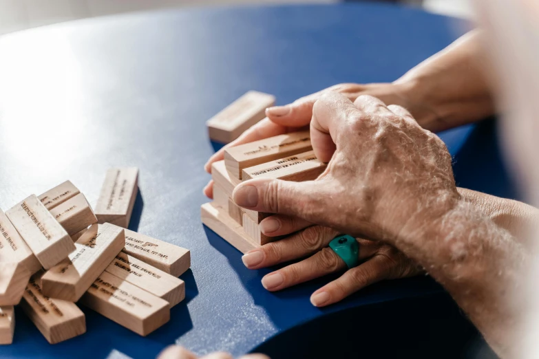 a person playing with wooden blocks on a table, by Emma Andijewska, unsplash, dementia, engraved, schools, 15081959 21121991 01012000 4k