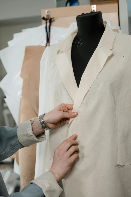 a person working on a suit on a mannequin, inspired by Alessandro Allori, trending on pexels, renaissance, wearing a white hospital gown, wearing jacket, wear's beige shirt, thumbnail