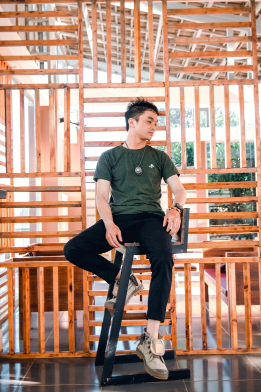 a man sitting on top of a wooden chair, inspired by Adam Dario Keel, pexels contest winner, green shirt, henry ascensio, wearing pants and a t-shirt, wooden structures