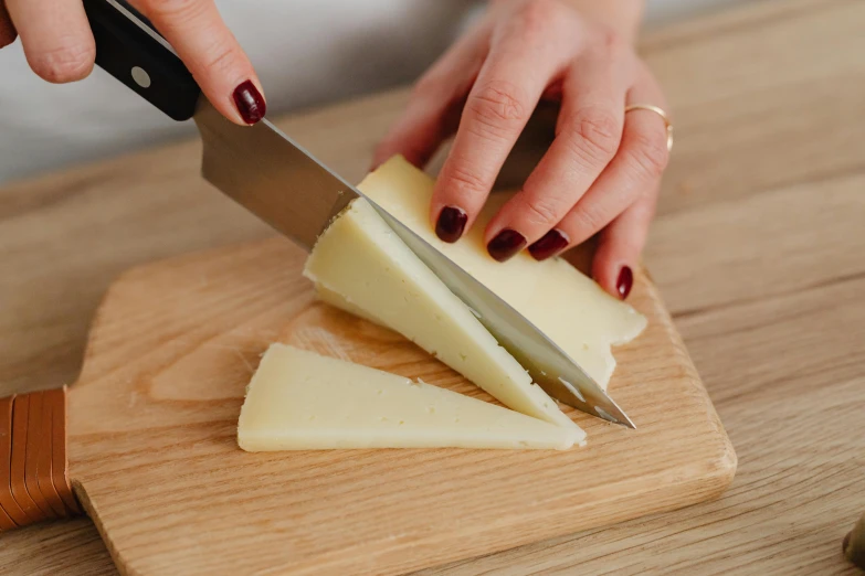 a person cutting cheese with a knife on a cutting board, inspired by Josefina Tanganelli Plana, pointè pose, crispy quality, honest, easy