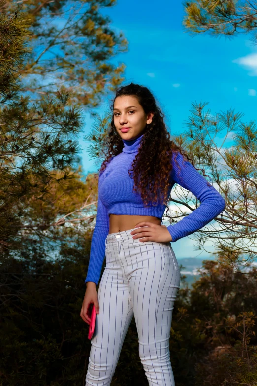 a young woman poses with her hands on her hips