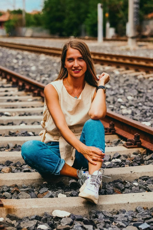 a woman is sitting on the train tracks, a portrait, by Lucia Peka, pexels contest winner, outfit : jeans and white vest, slightly tanned, solid background, low quality photo