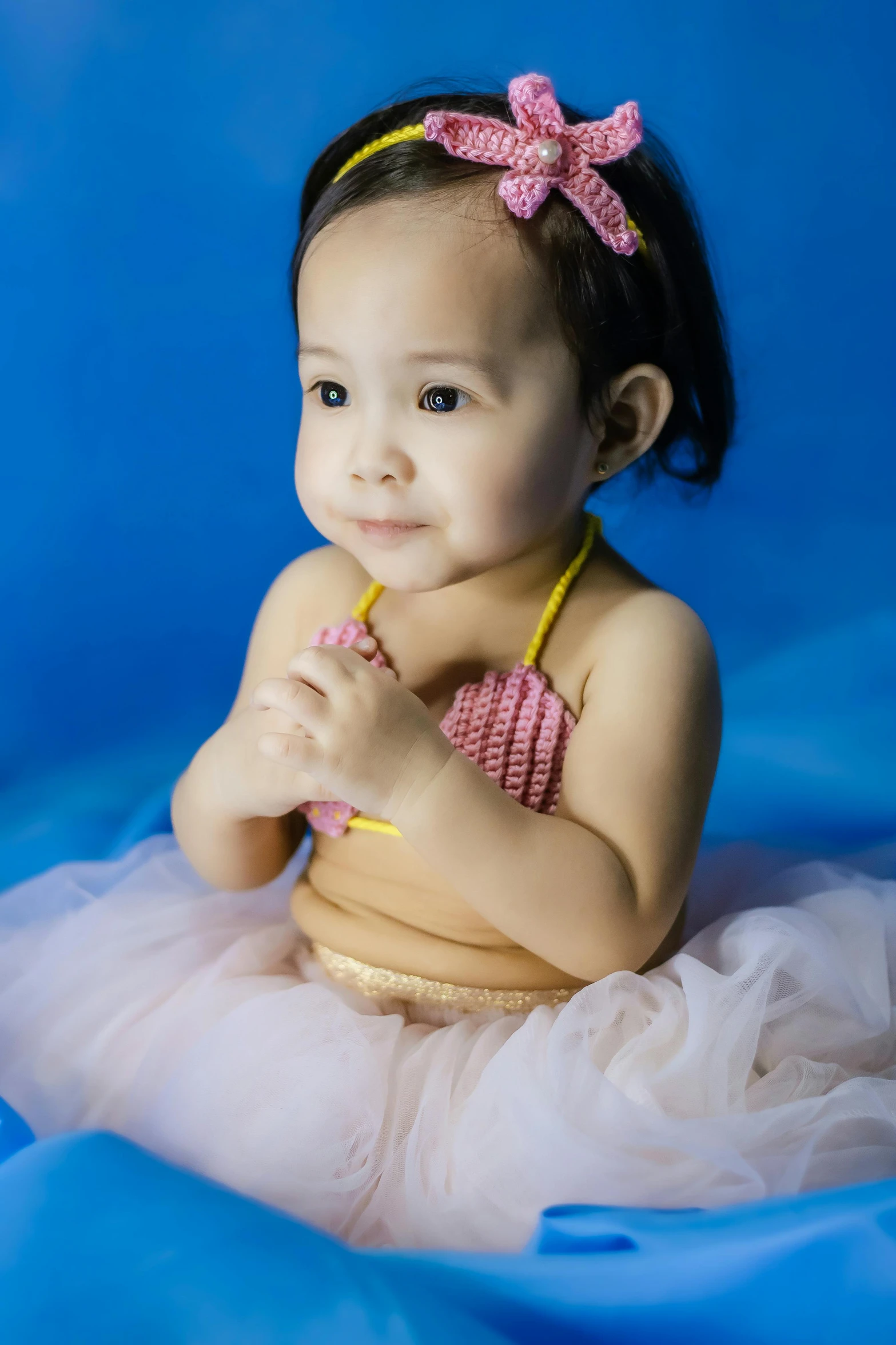 a baby girl wearing a swim suit sitting in the water