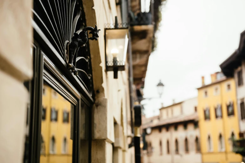 a couple of people walking down a street next to a building, by Giuseppe Avanzi, pexels contest winner, renaissance, wrought iron, view from across the street, black windows, gold and luxury materials