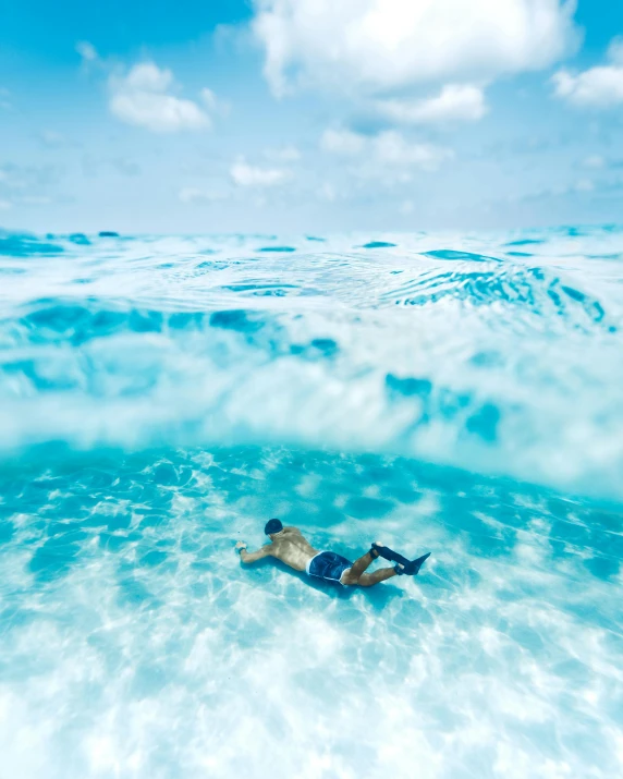 a man laying on a surfboard in the ocean, by Elaine Hamilton, unsplash contest winner, shades of blue, underwater bubbles, white beaches, inside the curl of a wave