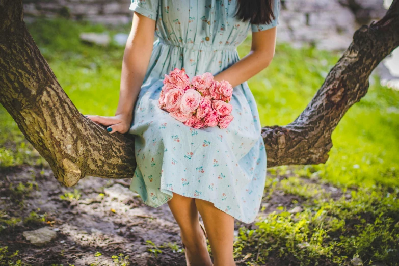 a woman sitting on a tree branch holding a bouquet of flowers, inspired by Elsa Bleda, pixabay contest winner, feminine girly dress, pink and teal, on a sunny day, peasant dress