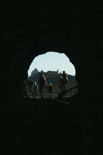 a group of people riding bikes through a tunnel, a picture, pexels contest winner, conceptual art, shadowy castle background, black round hole, standing before ancient ruins, view from inside