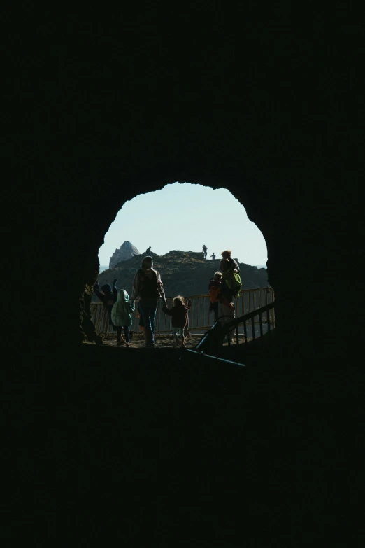 a group of people riding bikes through a tunnel, a picture, pexels contest winner, conceptual art, shadowy castle background, black round hole, standing before ancient ruins, view from inside