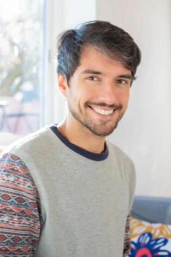 a man standing in a living room holding a remote, inspired by Germán Londoño, smiling :: attractive, mid - length hair, profile image, wearing casual clothes