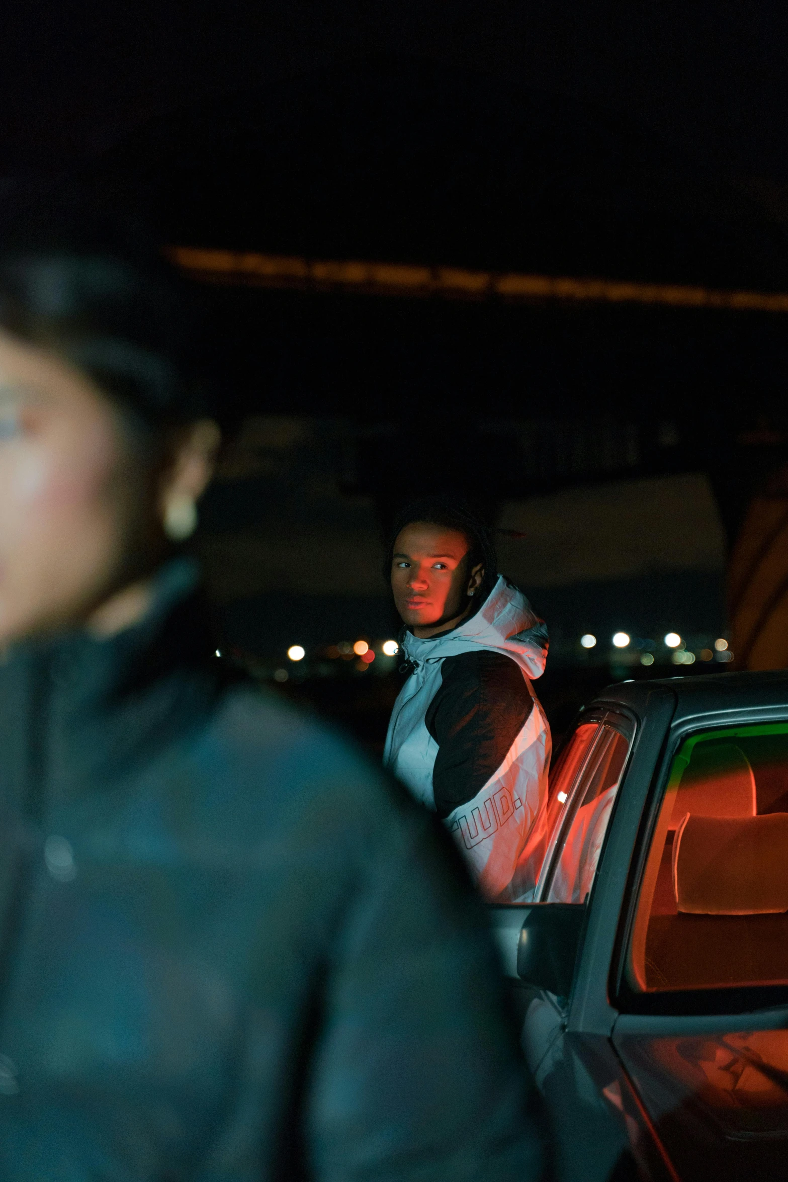 two people in coats standing near a parked car