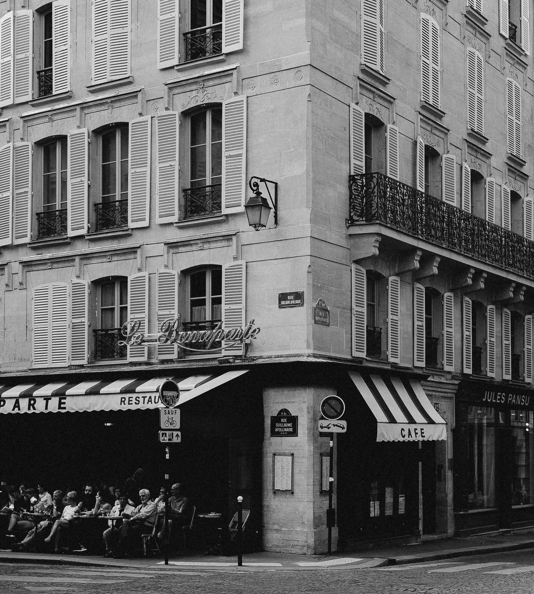 a black and white photo of a street corner, inspired by Brassaï, pexels, art nouveau, sitting in a cafe, 1980s photo, directoire style, pastelle