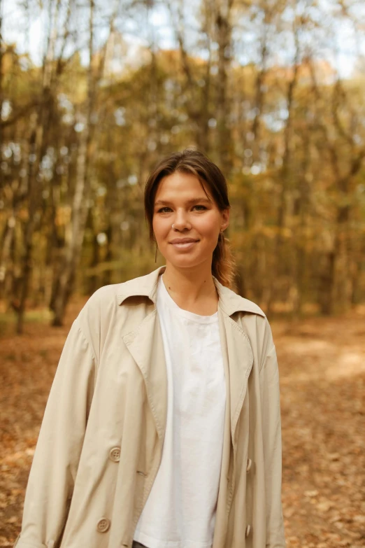 a woman standing on a dirt road in the woods, a portrait, pexels, wearing a long beige trench coat, viktor orban in a forest, portrait image, 🚿🗝📝