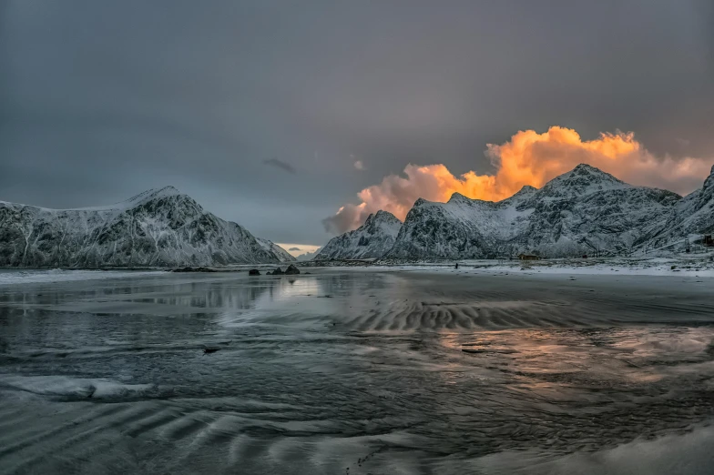 the sun peeks through clouds over a mountain range