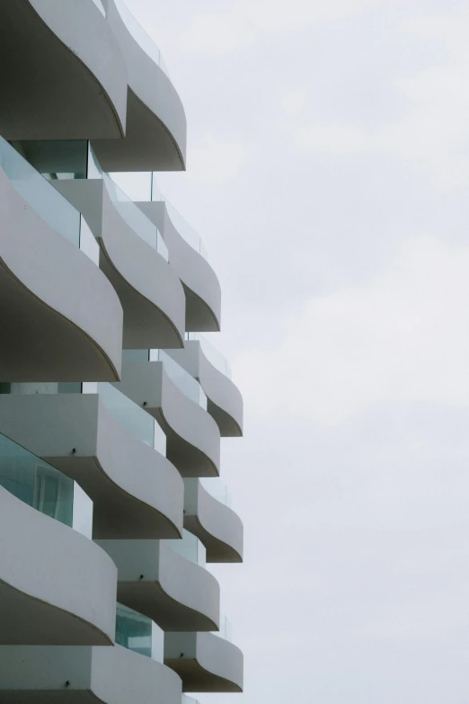 a tall building with many balconies on top of it, an abstract sculpture, unsplash, ibiza, low quality photo, sinuous, overcast skies