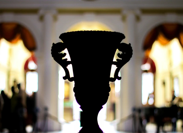 a black vase sitting on top of a table, a marble sculpture, by Dan Content, unsplash contest winner, neoclassicism, smithsonian museum, palace of the chalice, lit from behind, large head