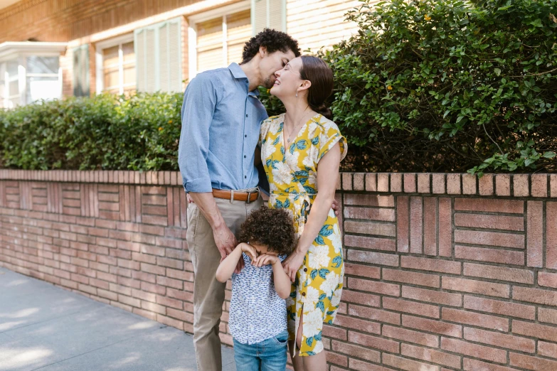 a man and woman kissing in front of a brick wall, by Carey Morris, pexels contest winner, portrait of family of three, finn wolfhard, 15081959 21121991 01012000 4k, summertime