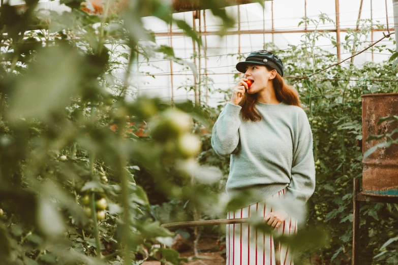 the woman is talking on her cell phone in a greenhouse