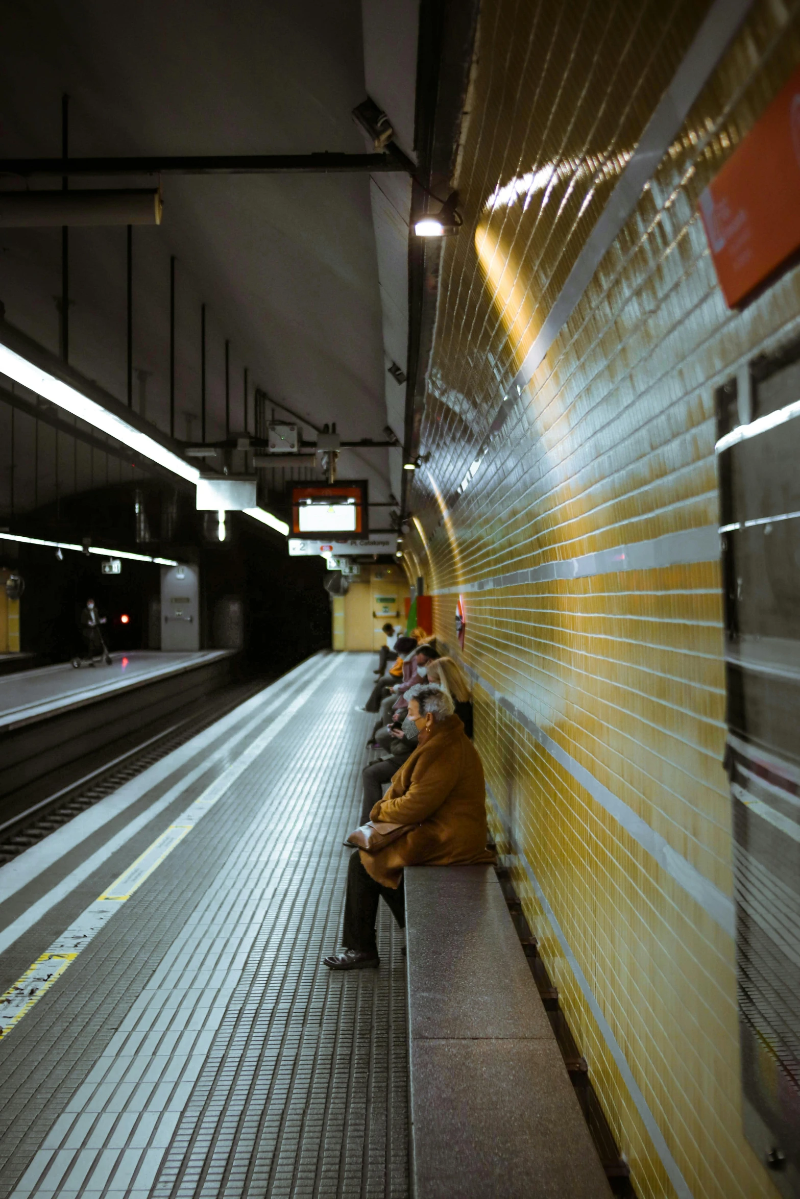 a group of people sitting on a bench next to a train, inspired by Andreas Gursky, unsplash, hyperrealism, yellow light, underground facility, buenos aires, 8k octan photo