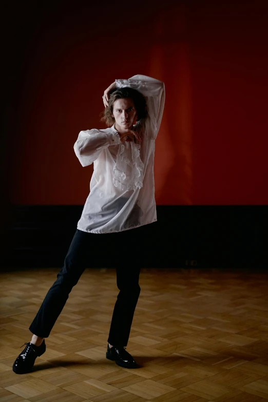 the woman is dancing and wearing a white shirt and black pants